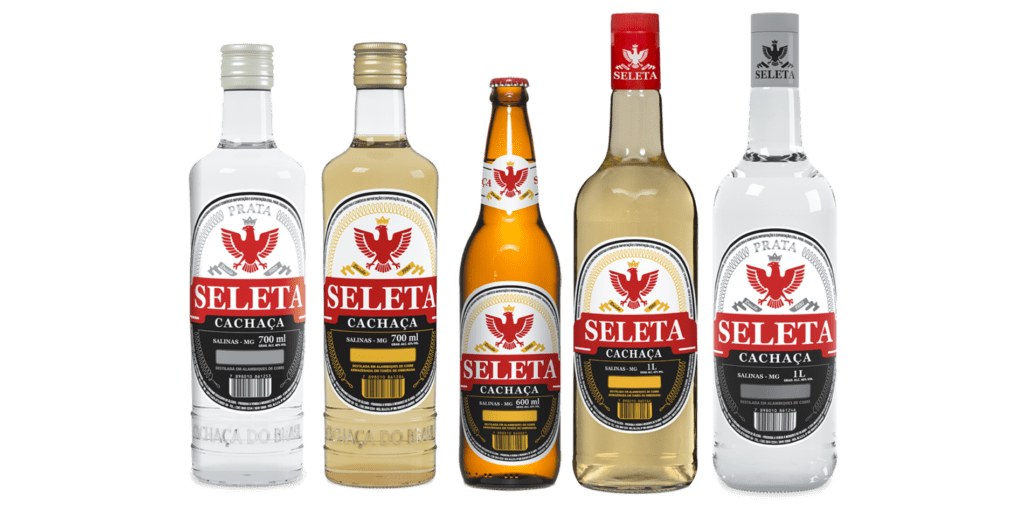 Enfileiramento de cinco garrafas diferentes da Cachaça Seleta, incluindo os formatos de 600ml e 700ml, apresentando os novos rótulos das linhas Prata e Ouro.