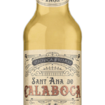 Fotografia frontal de uma garrafa da Cachaça Sant'Ana do Calaboca versão Ouro em fundo preto. O líquido dourado contrasta harmoniosamente com o rótulo de fundo creme e detalhes em ouro e cobre.